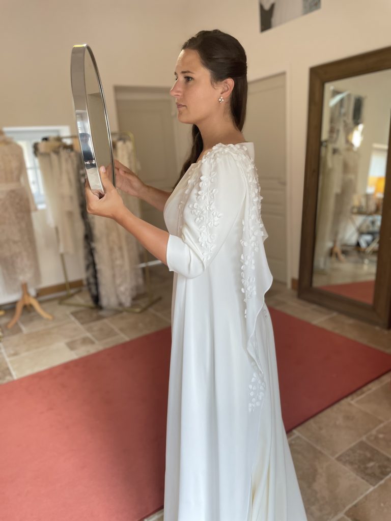 Femme en robe de mariée sur mesure Maison Jasmée qui se regarde dans un miroir