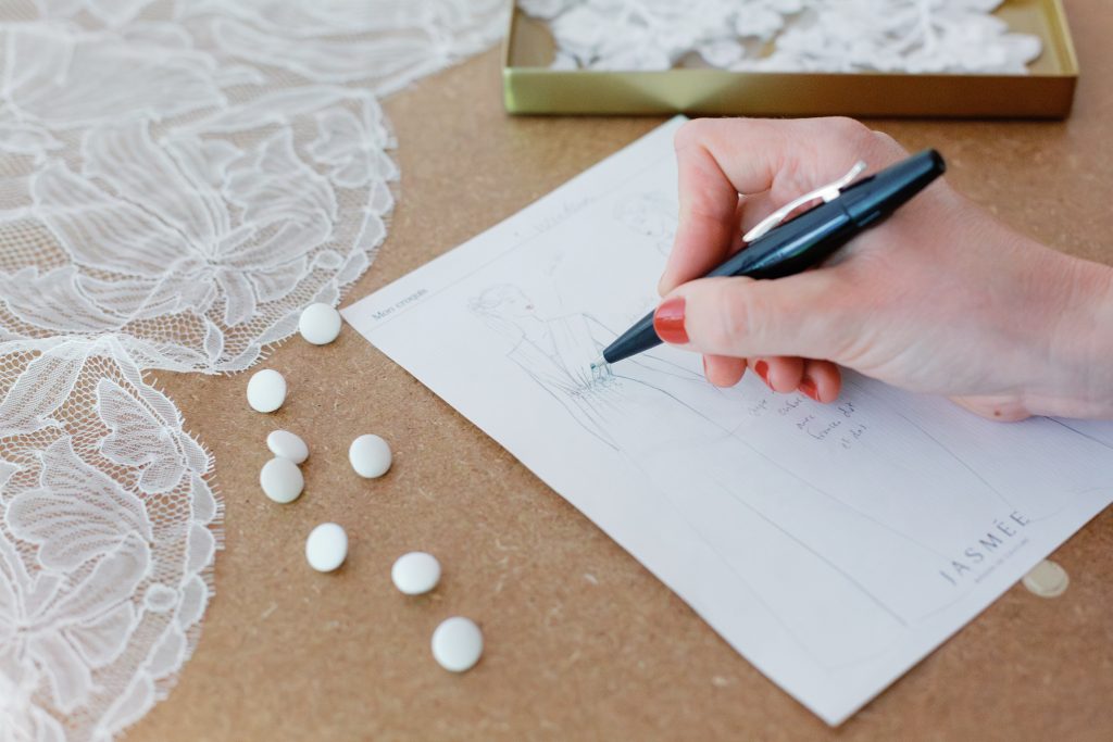 Main dessinant un croquis de robe de mariée.