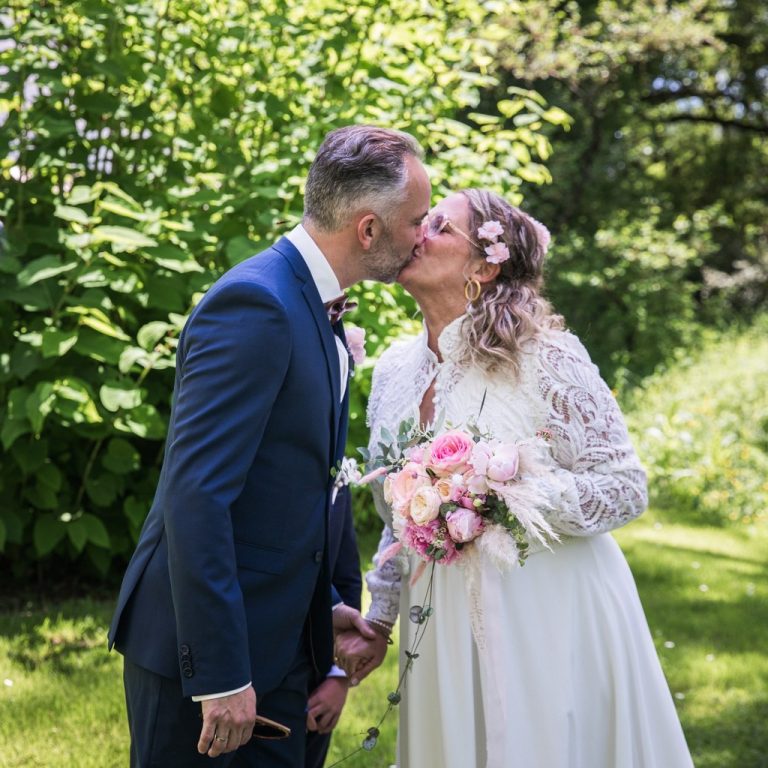 Couple de mariés qui s'embrassent. La femme porte une robe Maison Jasmée.