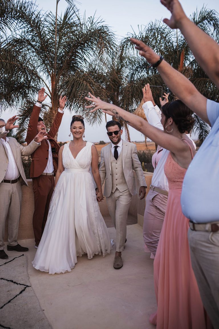 Couple de mariés passant au centre d'une haie d'honneur formée par leurs invités.