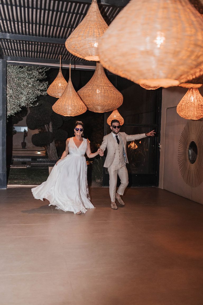 Couple entrant dans la salle de leur mariage. Ils se tiennent la main et avance en rigolant.