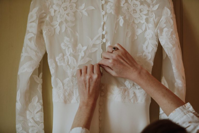 Femme déboutonnant sa robe de mariée avant de l'enfiler