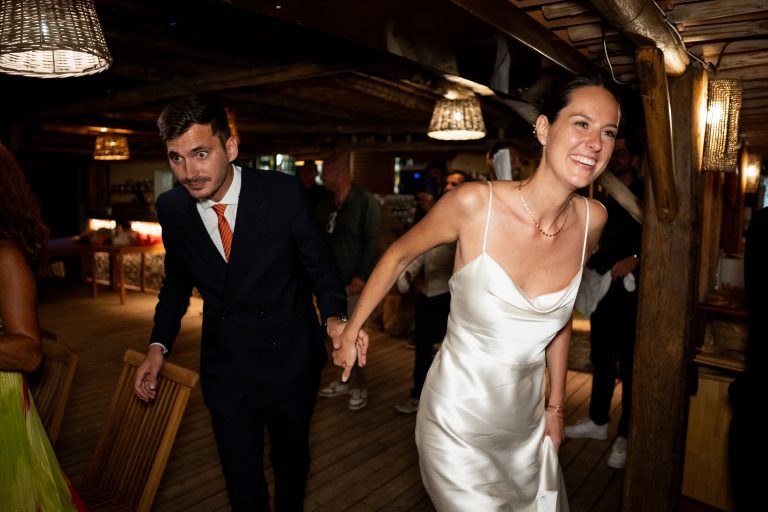 Deux mariés se tenant la main pour aller sur la piste de danse.