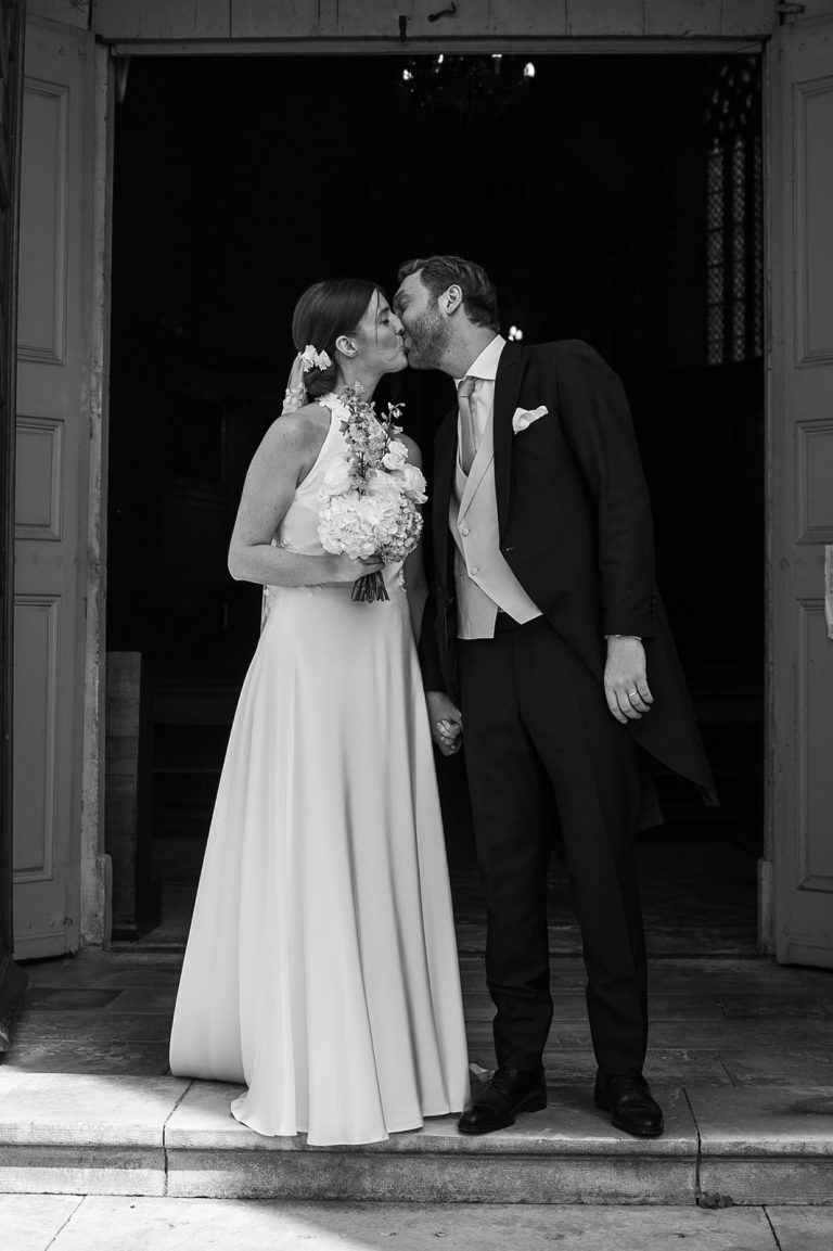 Couple de mariés s'embrassant devant l'église.
