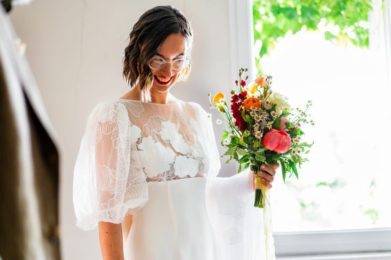 Mariée tenant un bouquet de fleurs colorées.