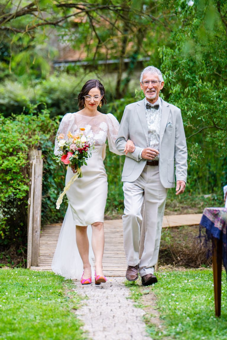 Mariée en robe Maison Jasmée arrivant au bras de son père.