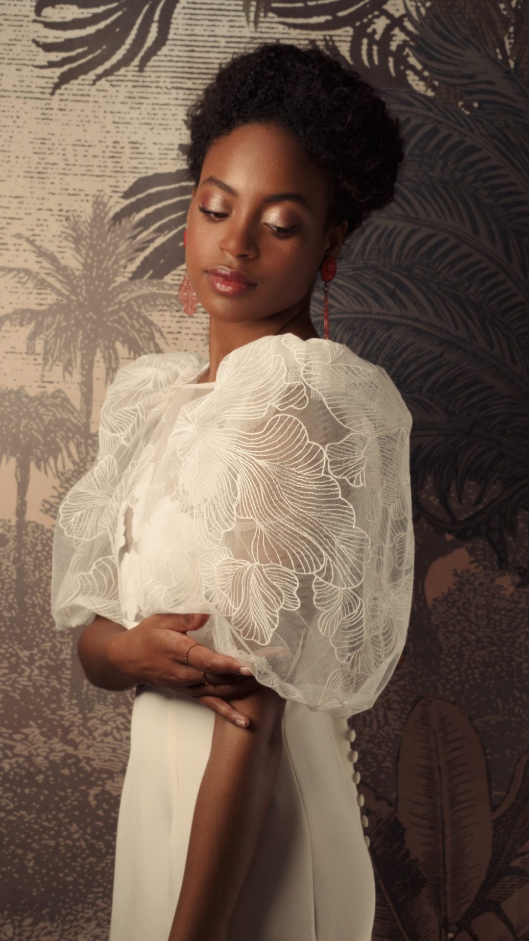 Femme debout de profil en robe de mariée sur mesure Maison Jasmée en tulle brodé et drap de soie avec des manches bouffantes